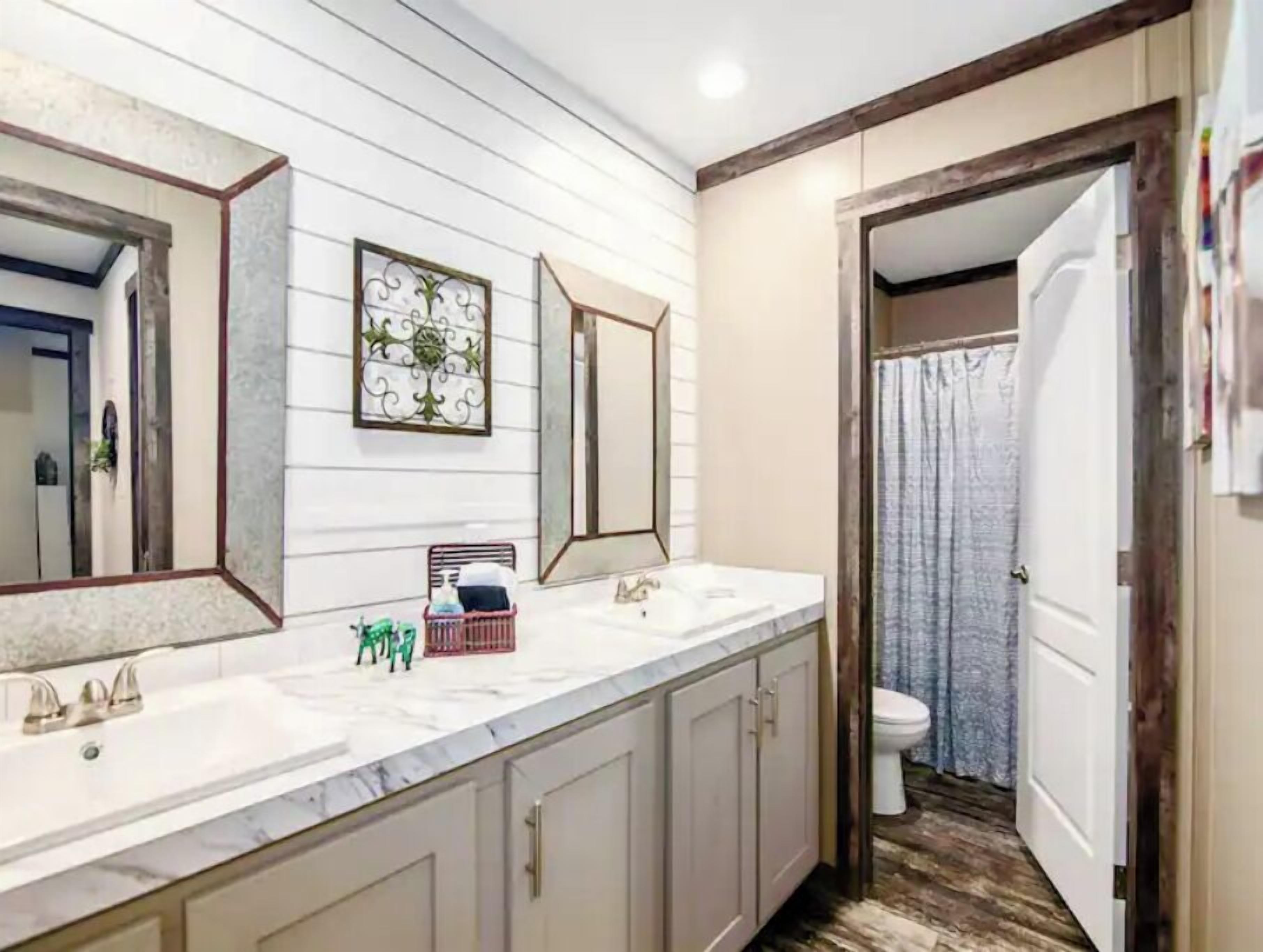 A bathroom with a white vanity, two mirrors, a sink, and a toilet.