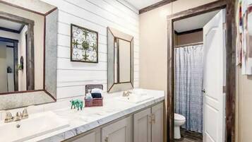 A bathroom with a white vanity, two mirrors, a sink, and a toilet.