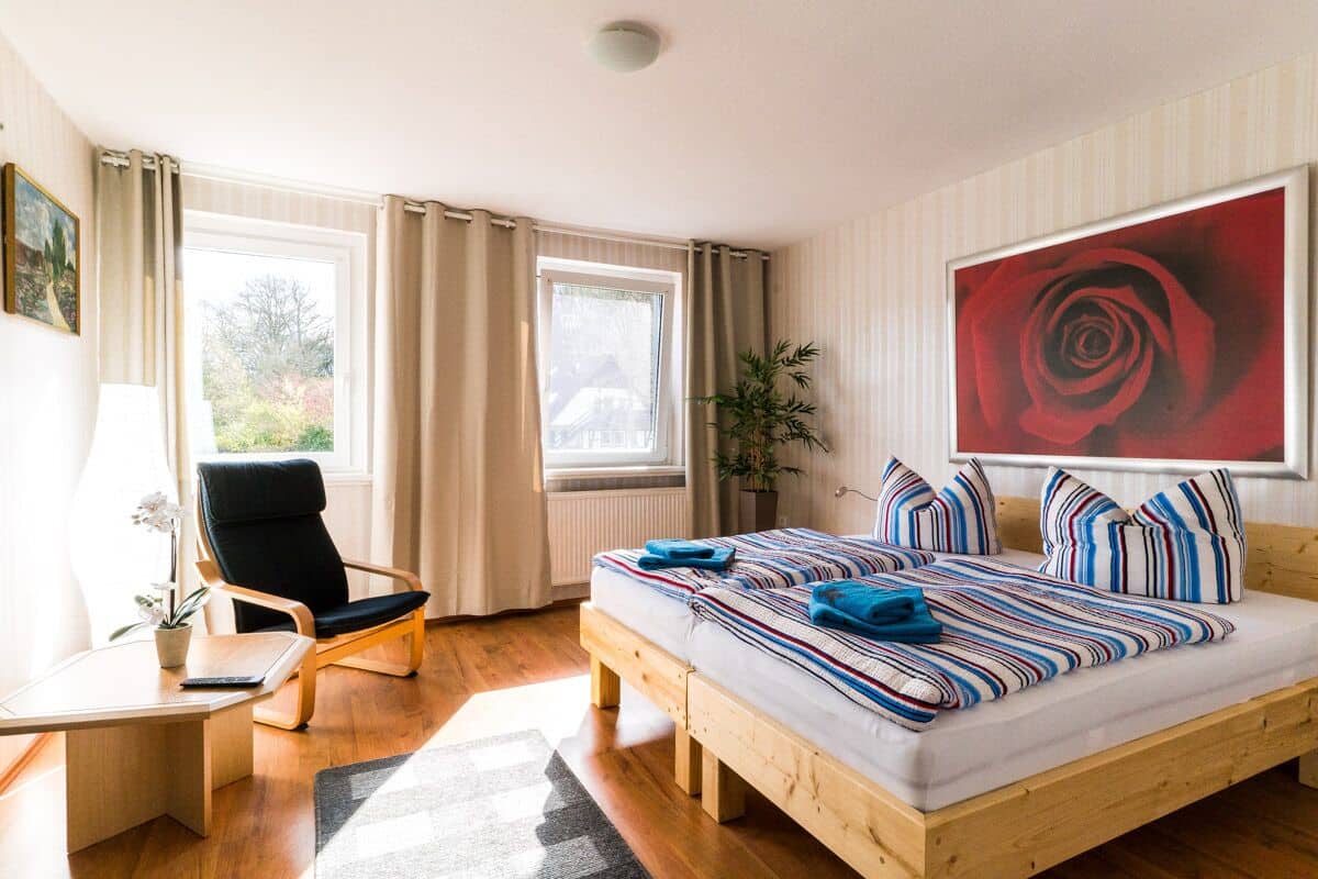 Une chambre à coucher avec un lit en bois, un bureau, une chaise et une grande fenêtre.