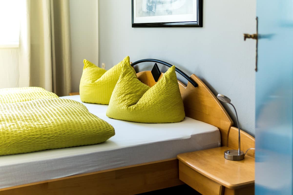 Un lit avec un cadre en bois, une table de chevet avec une lampe et un tableau accroché au mur.