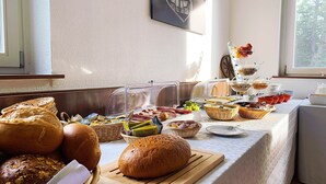 A breakfast buffet with various breads, pastries, and fruits. - Landhotel Prälank (Neustrelitz)