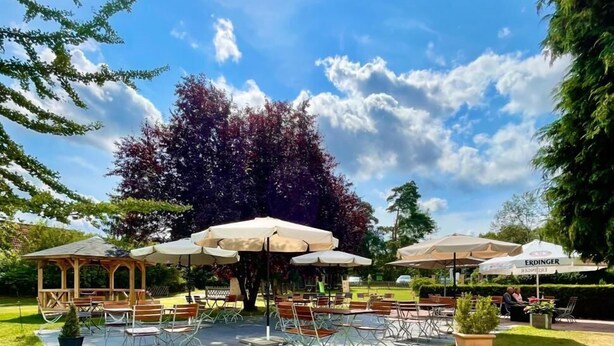 An outdoor patio area with tables and chairs, umbrellas, and a gazebo. - Landhotel Prälank (Neustrelitz)