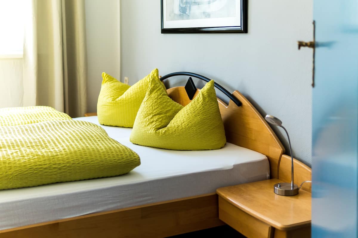 Un lit bien fait, avec un matelas blanc et un oreiller jaune à texture.