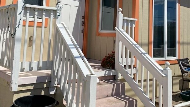 A two-story house with a porch, a front door, and a window.