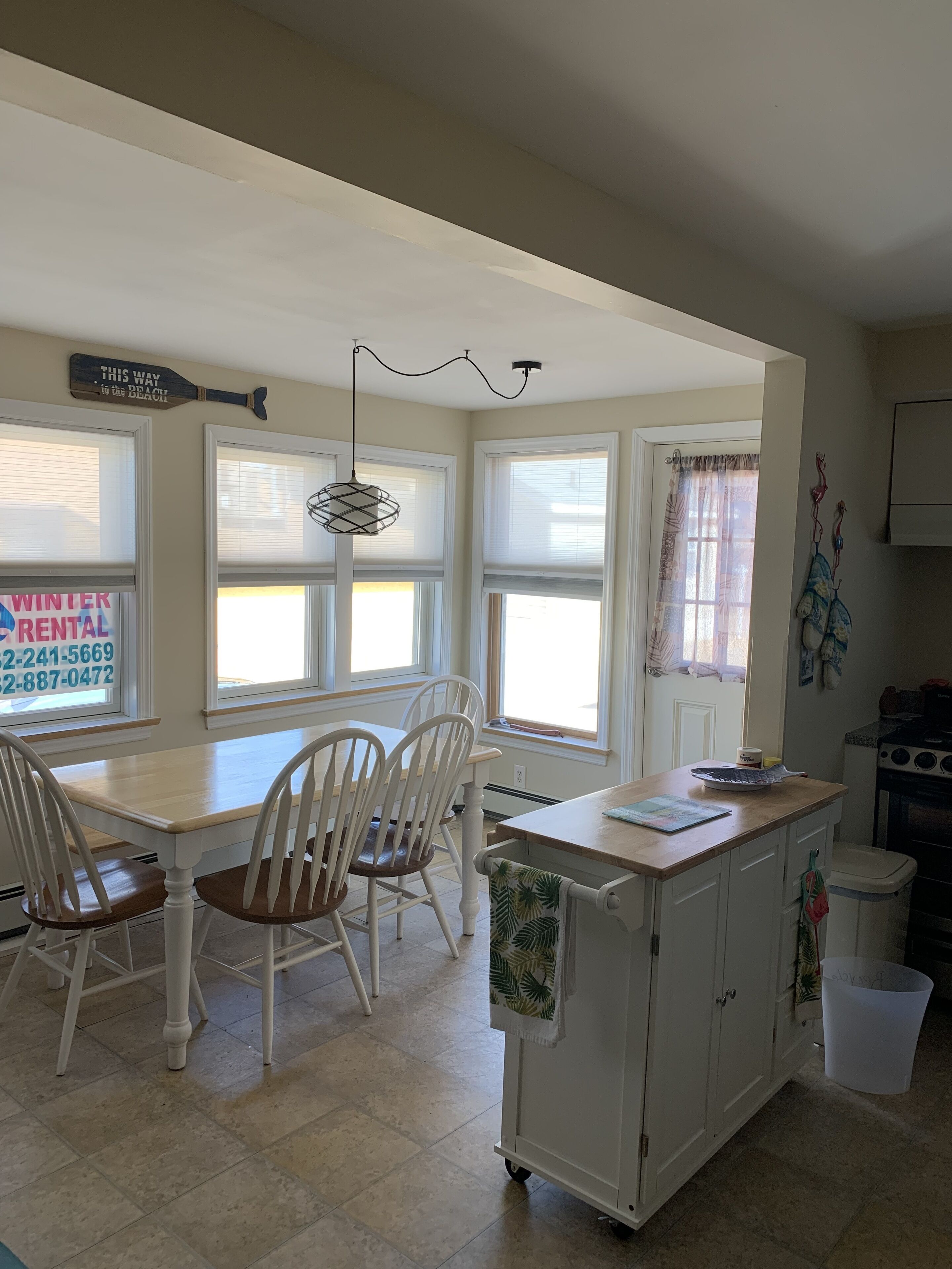 A kitchen with white cabinetry, a dining table with chairs, a small island with a countertop, and a window with a view.