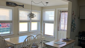 A kitchen with white cabinetry, a dining table with chairs, a small island with a countertop, and a window with a view.