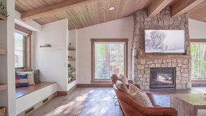 A spacious living room with a stone fireplace, built-in seating, and large windows. - Dreamy home on river, mountain views, steps from town. (Frisco)
