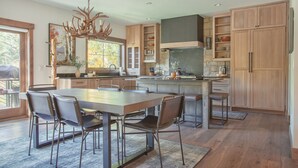 A spacious kitchen with a large island, wooden cabinets, and a chandelier. - Dreamy home on river, mountain views, steps from town. (Frisco)