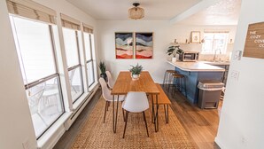 Een moderne keuken met een houten eettafel, witte stoelen en een groot raam.