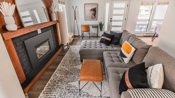 Een moderne woonkamer met een open haard, een grijze modulaire bank en een grote spiegel.