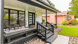 Een huis met een veranda, een bankje en twee stoelen.