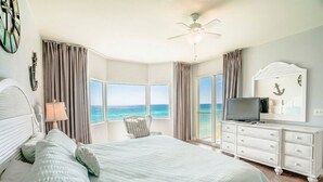 Un dormitorio con una cama grande, televisión, cómoda y vista al océano.