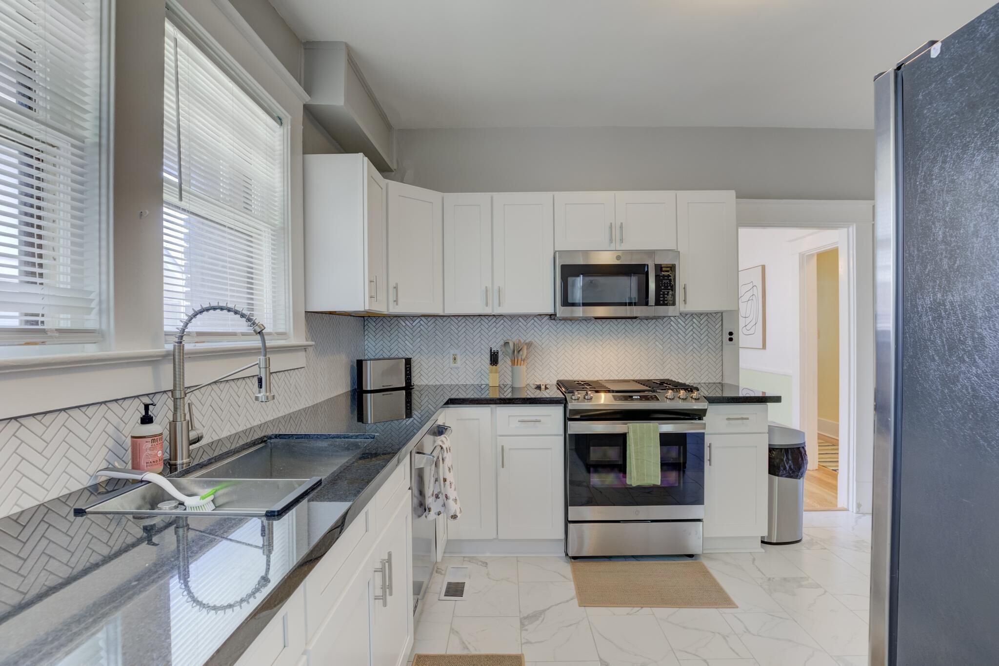 A modern kitchen with white cabinets, a stainless steel microwave, and a built-in oven.
