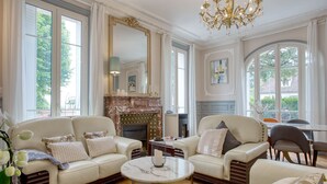 Een ruime woonkamer met twee banken, een open haard en een kroonluchter.