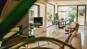 Ein geräumiger Wohnbereich mit Fernseher, Sofa und Esstisch.