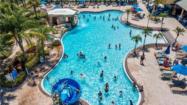 A large outdoor swimming pool surrounded by palm trees and lounge chairs. - 6BR Villa|Saltwater Pool•Movie Theater|Disney (Kissimmee)