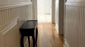 Ein Flur mit Holzboden und weißer Wandverkleidung.
