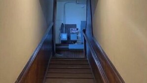 Eine Treppe führt zu einer Zwischenebene mit einer Deckenleuchte.