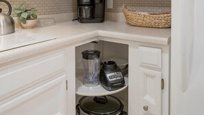 Een keuken met witte kastjes, een koffiezetapparaat, een waterkoker en een slowcooker.