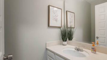 A bathroom with a white sink, a mirror, and two framed floral pictures on the wall.