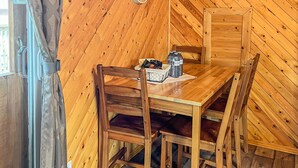Et hyggeligt trærum med et bord og stole, en hængende lampe og et vindue med gardiner.