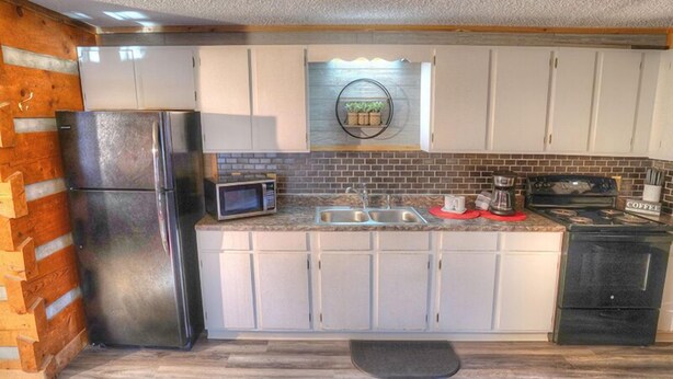 A kitchen with white cabinets, a stainless steel refrigerator, a microwave, a sink, and a coffee maker. - Studio B on Main St in Helen - Walkable to restaurants and attractions (Helen)
