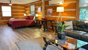 A log cabin interior with a bed, a couch, a dining table, and a potted plant. - Studio B on Main St in Helen - Walkable to restaurants and attractions (Helen)