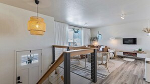 Ein modernes Wohnzimmer mit Wendeltreppe, Flachbildfernseher und Essbereich.