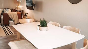 A modern dining area with a white table, wooden chairs, and a bench with a fur throw.