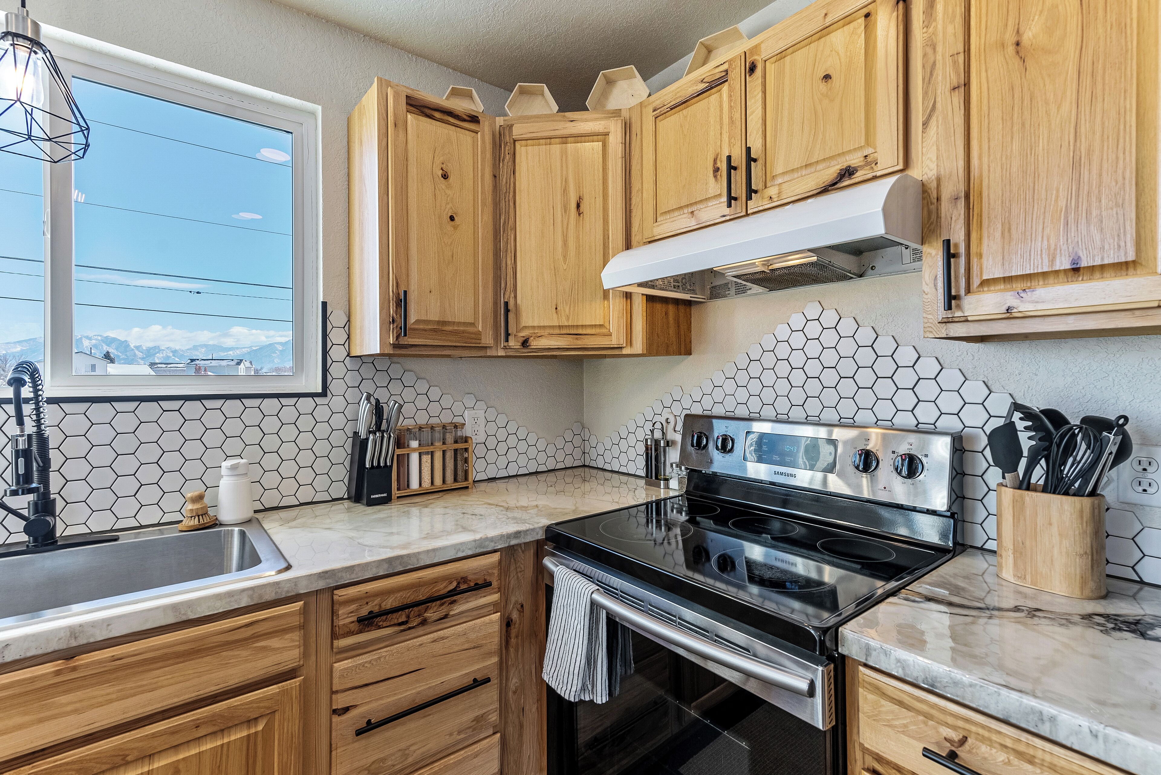A kitchen with wooden cabinets, a stainless steel stove, and a hexagonal tile backsplash.