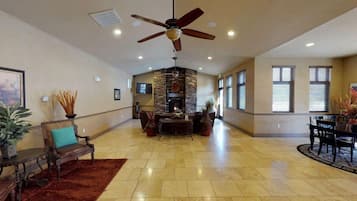 A spacious living area with a fireplace, a ceiling fan, and a dining area with a table and chairs.