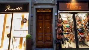 A building with a shop on the ground floor named "marcus Firenze" and another shop named "Roma1947" with a sale sign. - Borgo San Lorenzo 11 (Florence)