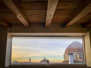 Ein Fenster mit Blick auf eine Stadtansicht, darunter ein glockenförmiges Gebäude und ein Turm.