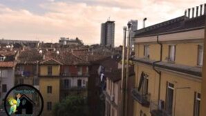 A view of a cityscape with buildings, including a tall skyscraper and a yellow building with balconies. - Apartment (Torino)