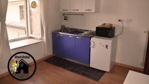 A compact kitchen with blue cabinets, a white refrigerator, and a microwave on top. - Apartment (Torino)