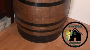 A large wooden barrel used as a table with a bottle of champagne, glasses, and a bottle of hand sanitizer on top. - Apartment (Torino)