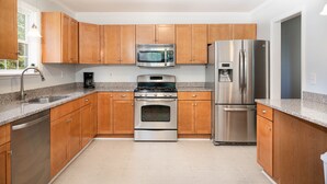 Una cocina moderna con armarios de madera, electrodomésticos de acero inoxidable, encimeras de granito y horno empotrado.