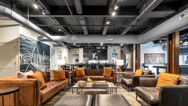 Ein modernes Wohnzimmer mit Ledersofas, einem Couchtisch und einem großen abstrakten Gemälde.