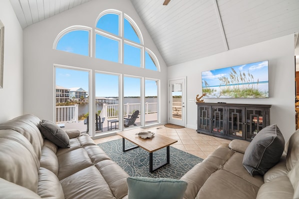 Relax in this stylish living room with a high ceiling, large windows, and a comfortable sofa and armchair.