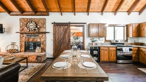 A spacious kitchen with a stone fireplace, wooden cabinets, and a dining area set for six. - Oak Creeks Sedona Oasis with Hot Tub, and Hiking (Sedona)