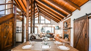 A dining area with a wooden table set for four, a stone fireplace, and a lofted ceiling with exposed beams. - Oak Creeks Sedona Oasis with Hot Tub, and Hiking (Sedona)