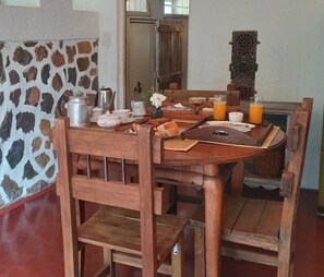 A wooden dining table with chairs, a stone wall, and a door in the background. - Casita Antigua Cerquita del Lago (Villa del Dique)