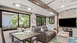 Un intérieur de camping-car confortable, comprenant un coin repas, un coin salon et une cuisine.