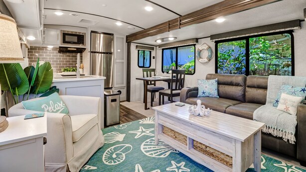 Un intérieur de camping-car compact comprenant un coin cuisine, un espace repas et un coin salon.