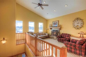A spacious living room with a fireplace, two sofas, a staircase, and a large window. - Large 3rd Fl Corner Unit, 2BR+Loft, 2.5BA, Sleeps 4 (Park City)