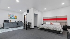 Ein modernes Hotelzimmer mit Bett, Schreibtisch, Küchenzeile und Badezimmer.