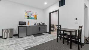 Eine kompakte Küche mit modernen Geräten, ein Essbereich mit Tisch und Stühlen sowie ein großes abstraktes Gemälde an der Wand.