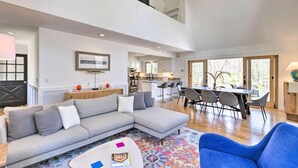 A spacious living area with a sectional sofa, a dining table with chairs, and a kitchen in the background. - Upscale Hamptons Home: 1 Mi to Sammys Beach! (East Hampton)