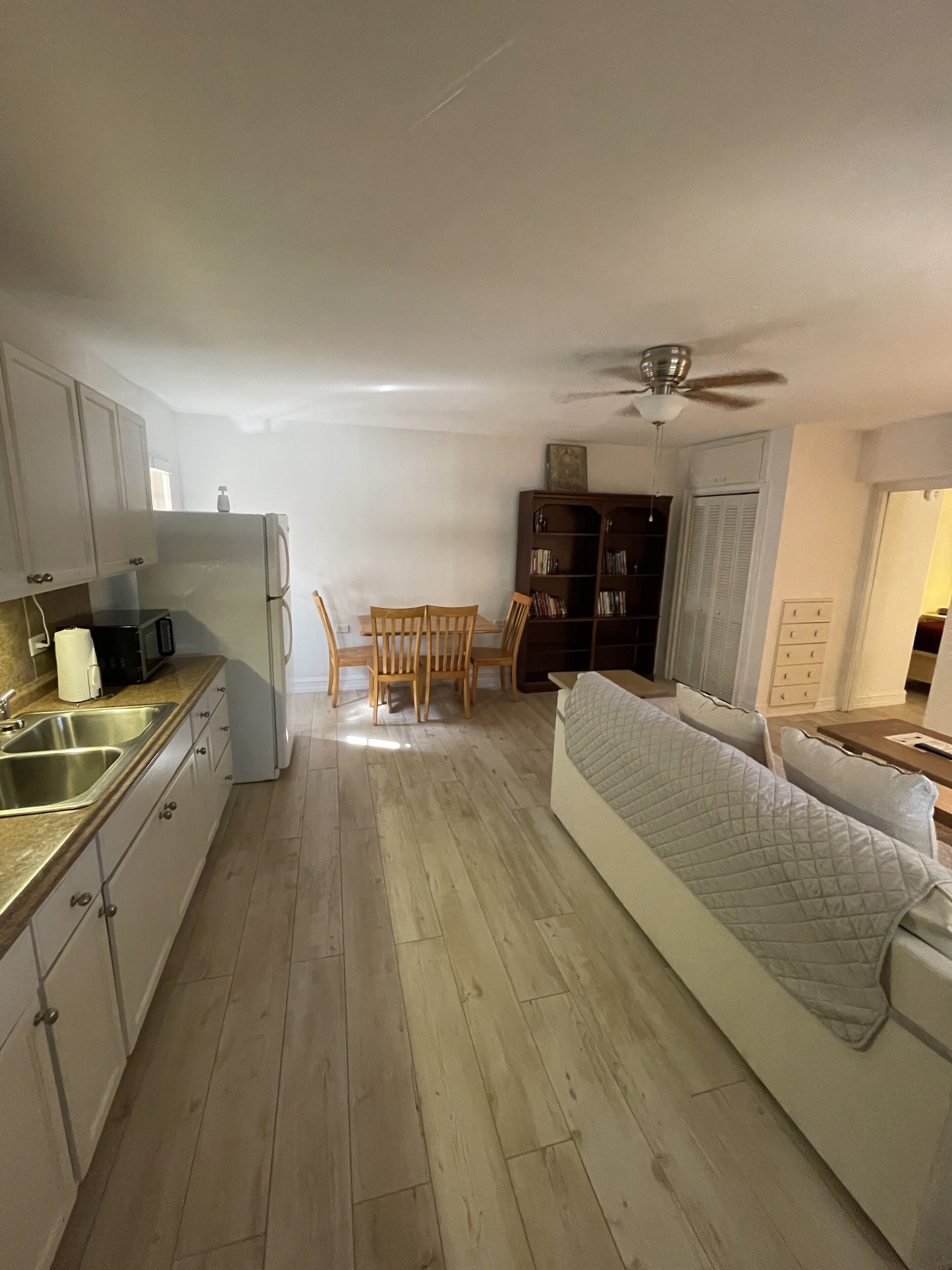 Een kleine leefruimte met kitchenette, eethoek en een bank.
