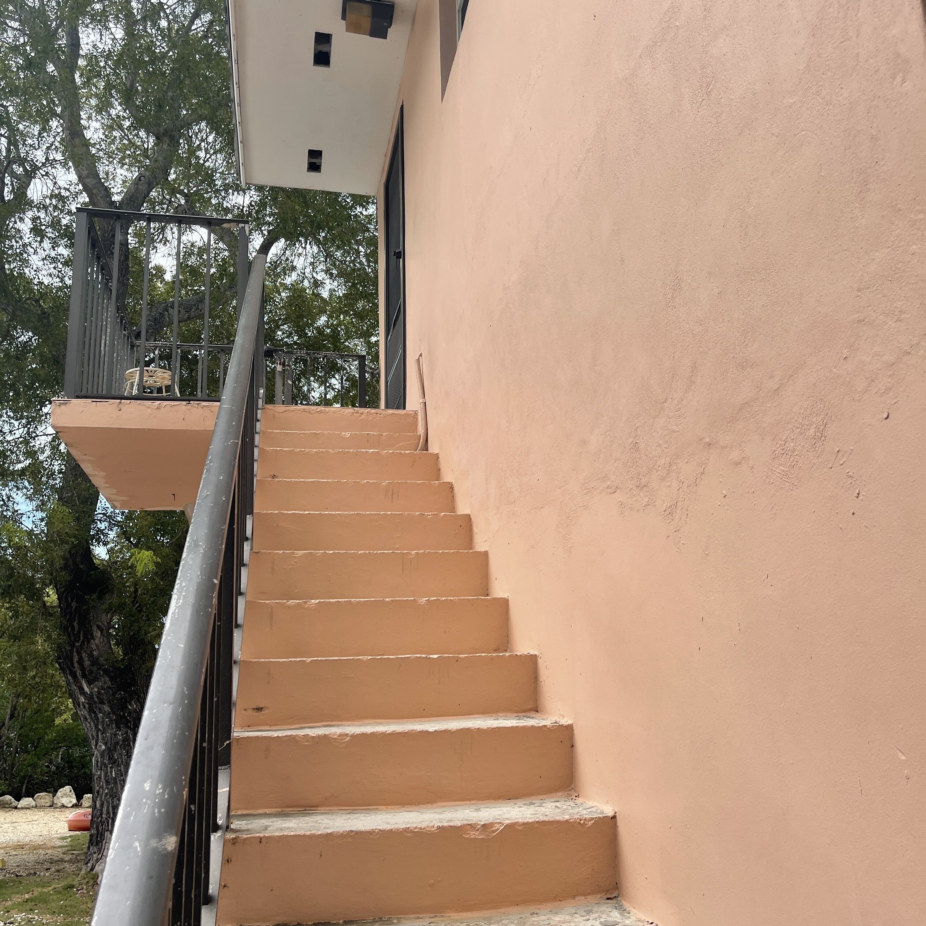 A staircase with a beige wall on one side and a metal railing.
